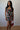 Woman wearing a floral dress holding a red bag against a plain background